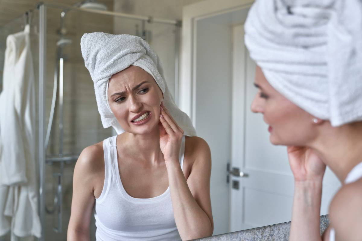 Caucasian woman in the bathroom having a strong toothache due to teeth grinding.